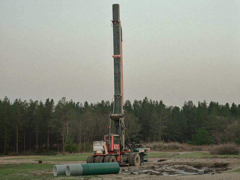 A water well drilling rig raised on a rural property